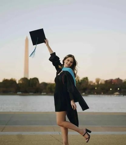 Emily Barton in graduation cap and gown in front of Washington Monument