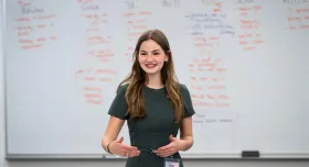 Emily Barton talking in front of a white board with columns of writing