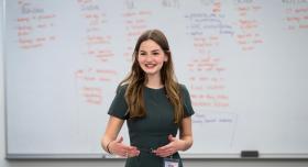 Emily Barton talking in front of a white board with columns of writing