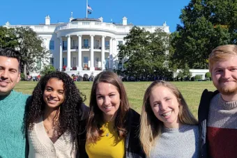 5 students pose with arms around each other in front of the White House