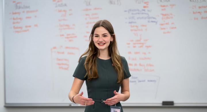 Emily Barton talking in front of a white board with columns of writing